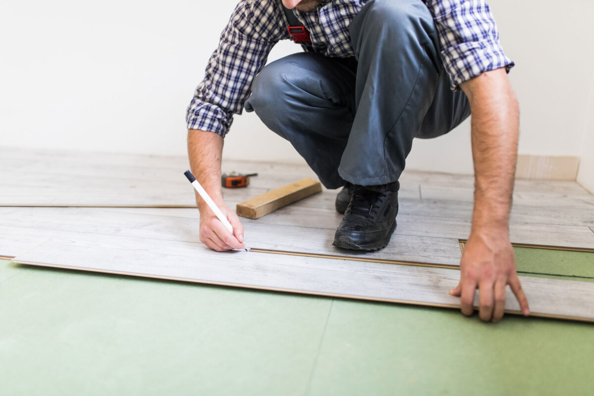 trabajador-joven-que-recubre-piso-tablas-piso-laminado